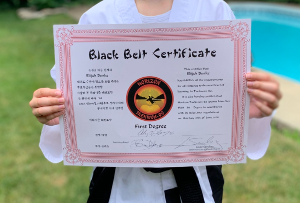 Elijah Burke holding his black belt certificate